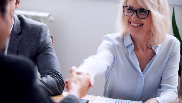 Smiling mature businesswoman handshaking businessman at meeting negotiation,