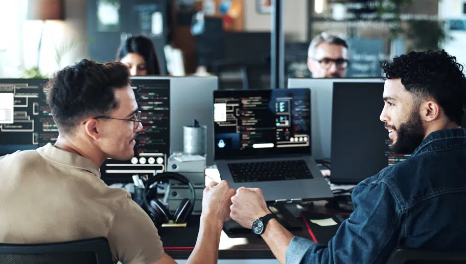 two programming engineers fist bump while smiling