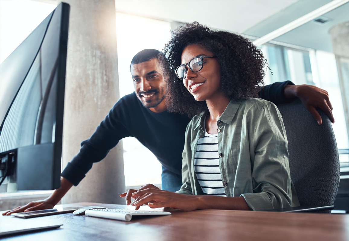 two people looking at a desktop monitor