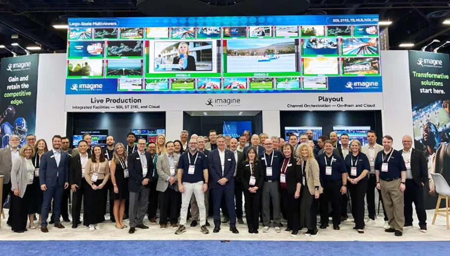 group photo of the Imagine Communications' team that attended NAB 2026 standing in front of our booth with the large overhead multiviewer screen