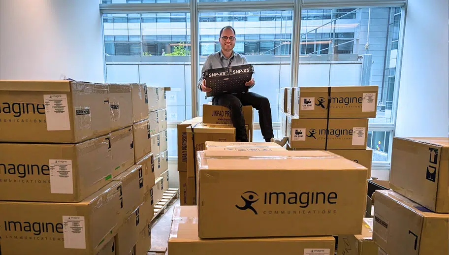 Imagine engineeer, Yannick Olivier, sits atop a large stack of SNP-XS in shipping boxes